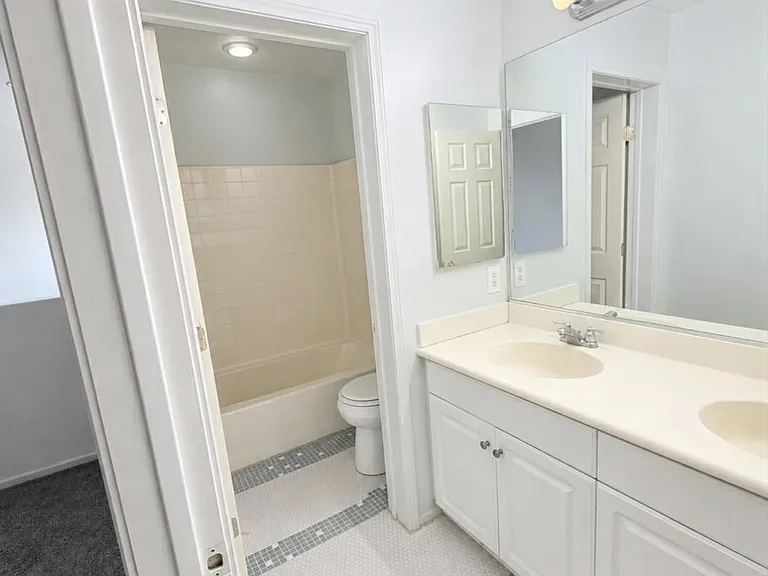 Upstairs full bathroom featuring a double-sink vanity and shower/tub combination.