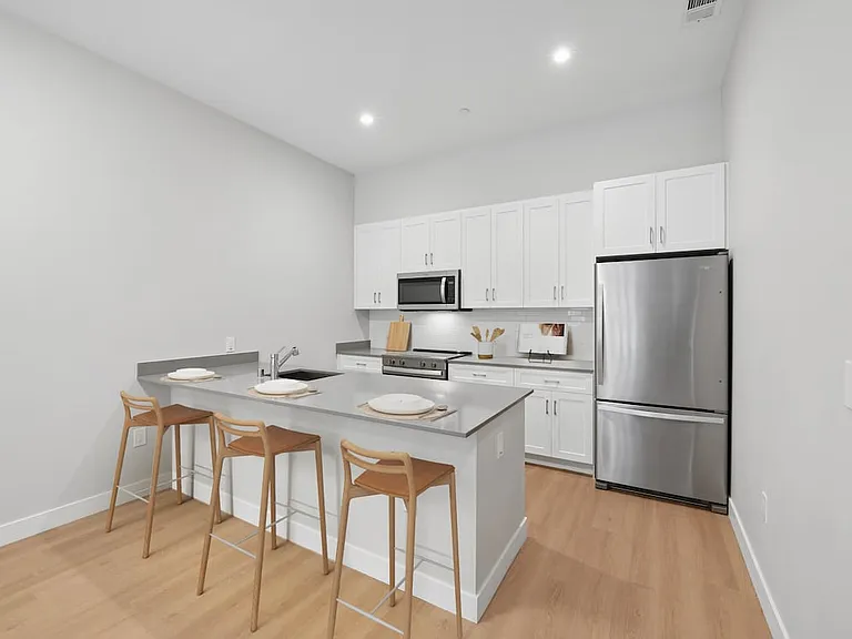 Upgrade Collection kitchen with stainless steel appliances, white cabinetry, grey quartz countertop, tile backsplash, and hard surface flooring