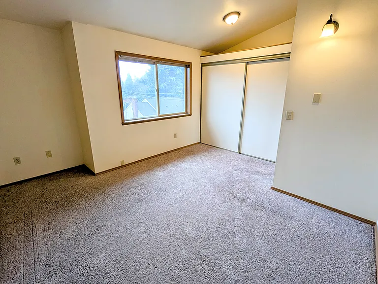 209 Primary bedroom with vaulted ceiling, large window, and closet