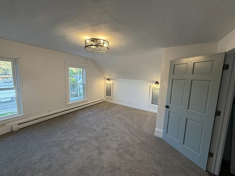 Bedroom - two windows to the south. Closet to the behind and to the left (can't see). Bed to the right. Overhead fan to circulate the air. Door to the right leads to the main room and bathroom.