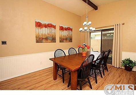 Formal dining has vaulted ceiling with beam and sliding glass do