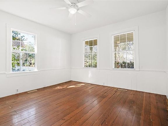 Empty room featuring visible vents, a ceiling fan, and wood finished floors