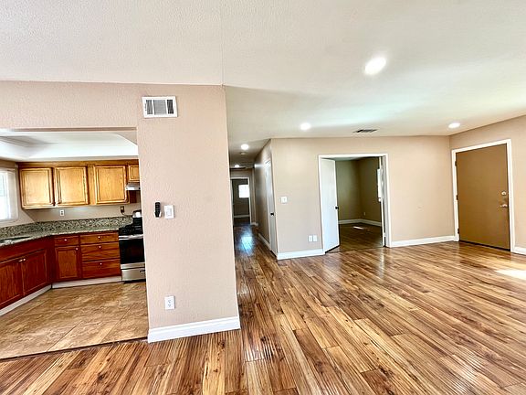 Open view of living room through out kitchen, and hallway leads to bedrooms