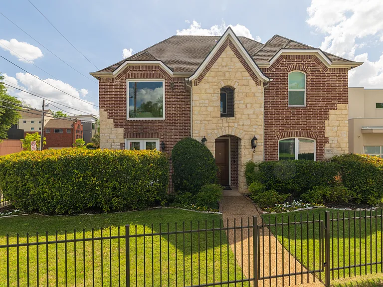 Beautiful brick and stone exterior with a gated front lawn