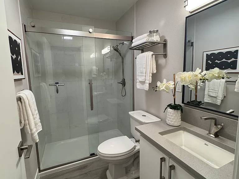 Stylish bathroom featuring quartz vanity, modern fixtures, and a walk-in tile and glass shower.