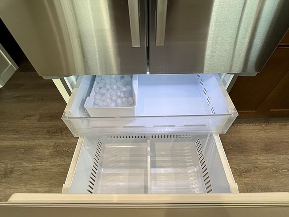 Full-sized refrigerator with ice maker and freezer storage.