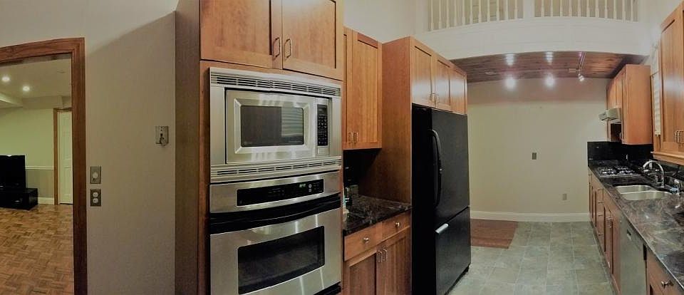 High ceiling granite top kitchen with stainless steel applia
