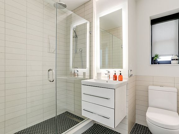 Bright tiled bathrooms with large backlit designer mirror, Hans Grohe chrome fixtures and Villeroy & Boch vanity