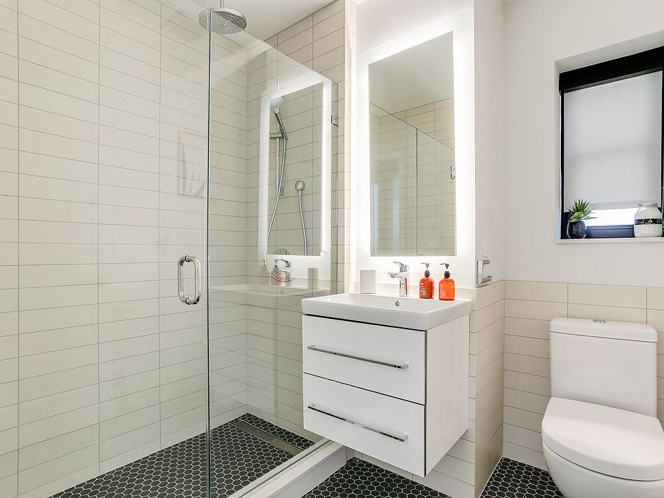 Bright tiled bathrooms with large backlit designer mirror, Hans Grohe chrome fixtures and Villeroy & Boch vanity