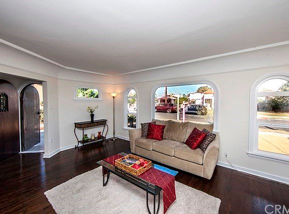 Enter bright living room with refinished hardwood floors, arched windows, coved ceiling.