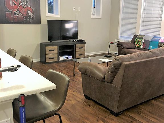 Open concept kitchen & living area with couch, loveseat, bar stools, quartz countertops, stainless steel appliances, tv