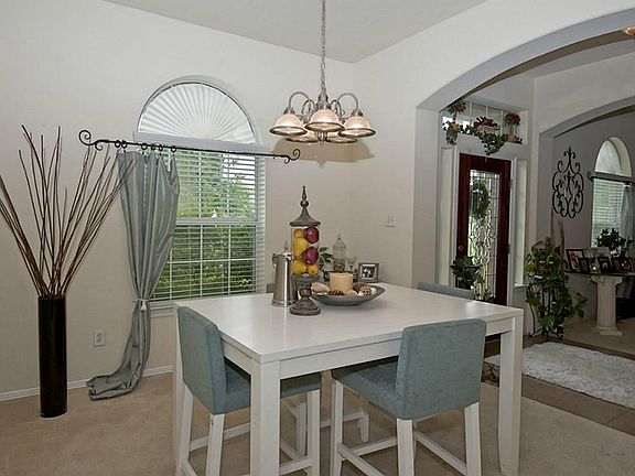 The formal dining room features a large arch top window for natural light, carpeting, and a decorati