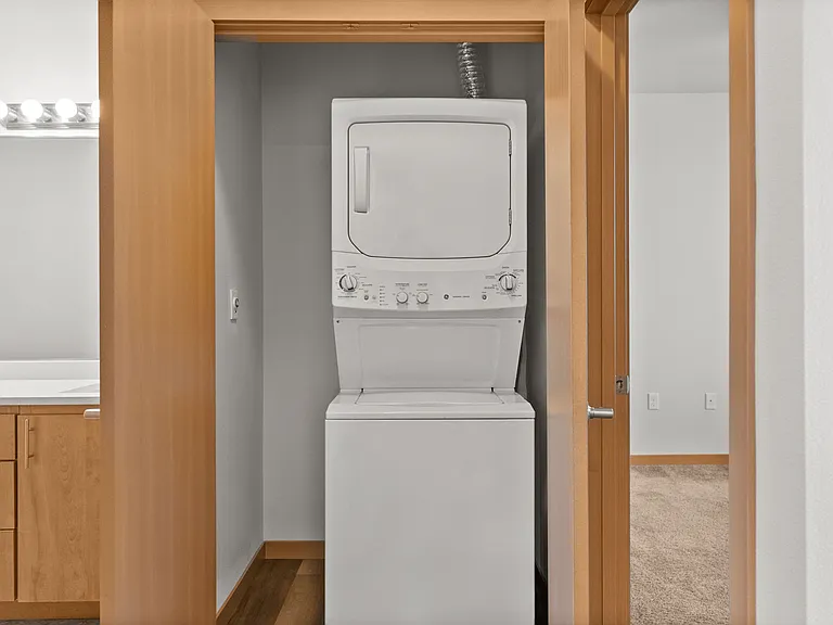 Compact laundry area featuring a modern stacked washer and dryer conveniently located in a spacious apartment. Compact laundry area featuring a modern stacked washer and dryer conveniently located in a spacious apartment.