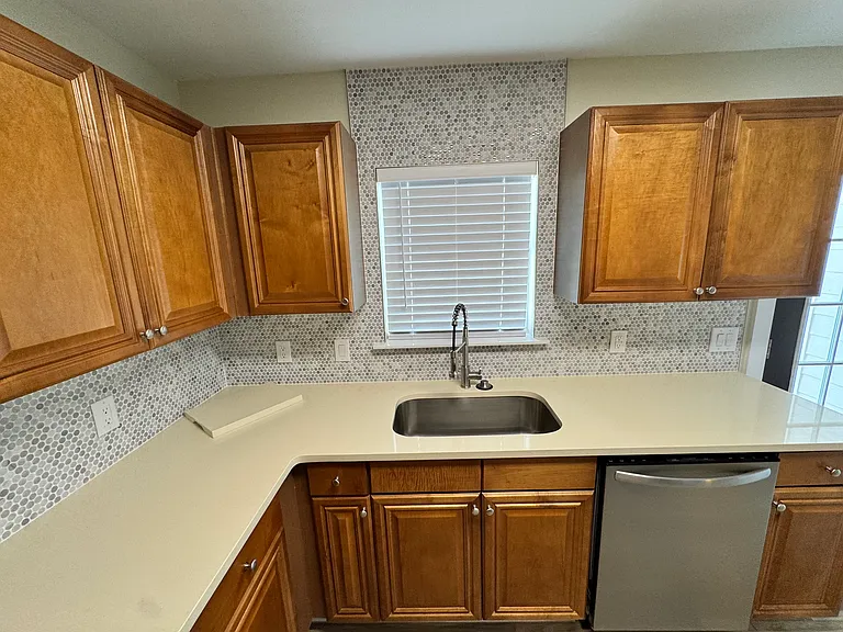 Kitchen with quartz counters, custom back splash, and single bowl kitchen sink with pull down faucet overlooking the back patio.
