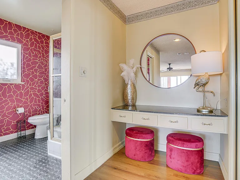 Bathroom with a glass shower, toilet area, and a separate vanity counter with mirror, lighting, and seating.
