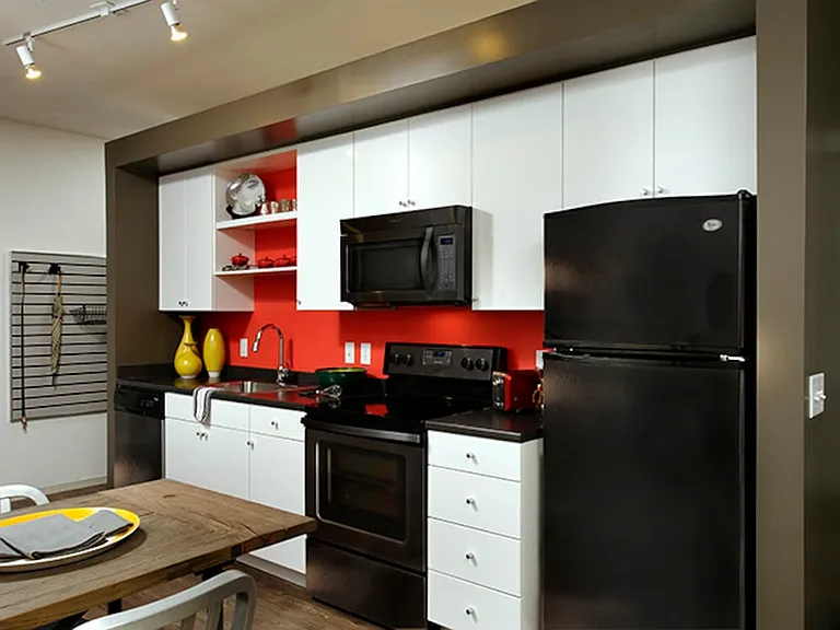Urban kitchen with white cabinetry, black countertops, and black appliances