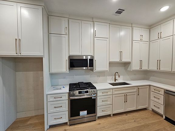 Luxury kitchenette includes an abundance of cabinets, quartz counters, a single basin sink, dishwasher, microwave, oven/gas range cooktop, and French door fridge/freezer.