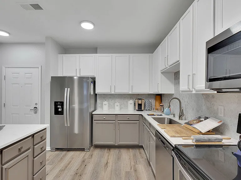 Elegant modern kitchen showcasing sleek stainless steel appliances, pristine white cabinetry, and stylish wood flooring, perfect for culinary creativity.