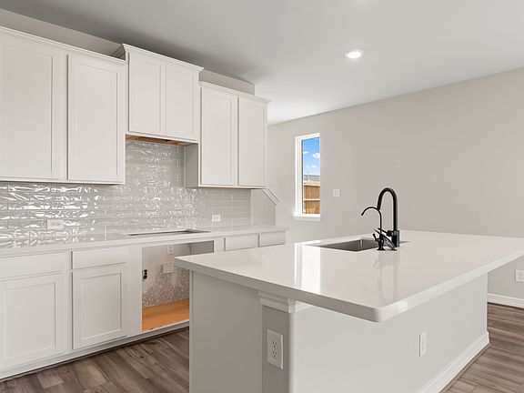 The kitchen features a center island with with light stained cabinetry, quartz countertops and a mod