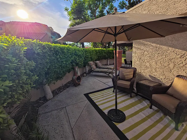 Secluded back patio with multiple seating areas and a large gas grill.