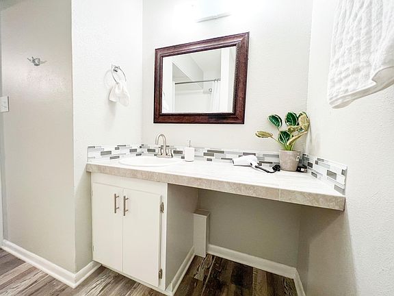 This fully renovated bathroom features a stylish vanity with a quartz countertop and modern tile backsplash.