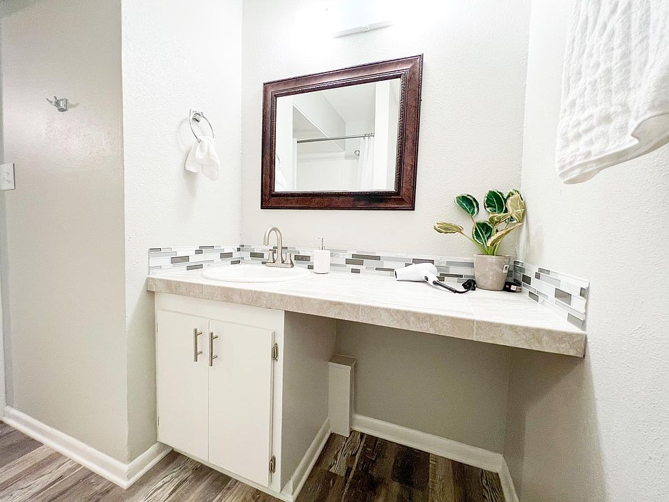 This fully renovated bathroom features a stylish vanity with a quartz countertop and modern tile backsplash.