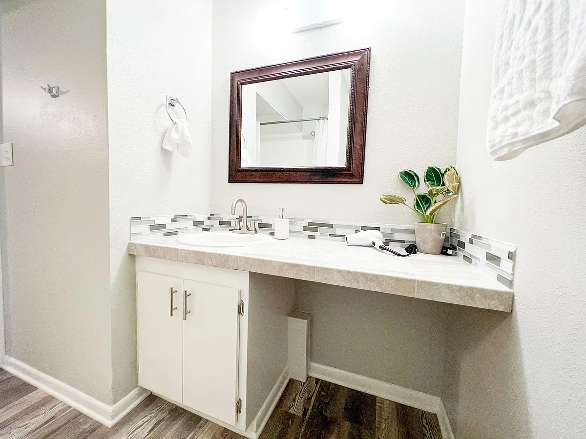 This fully renovated bathroom features a stylish vanity with a quartz countertop and modern tile backsplash. - 2125 Banita St #4