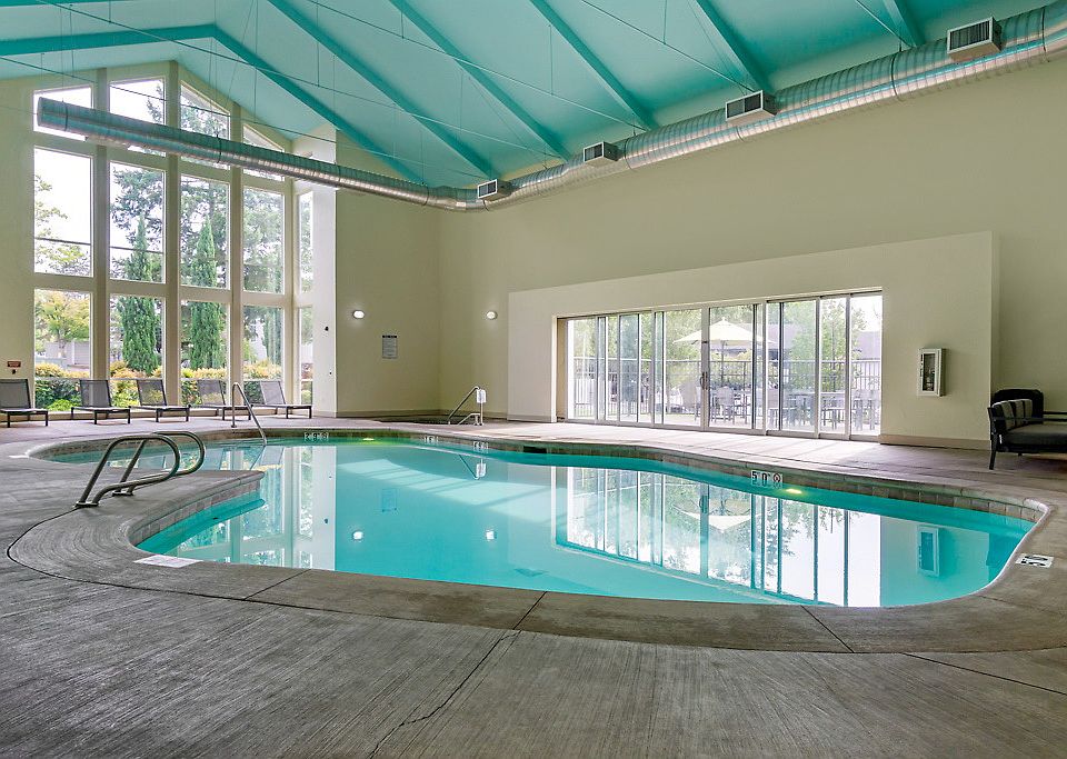 Interior swimming pool and spa in with large windows and a vaulted ceiling.