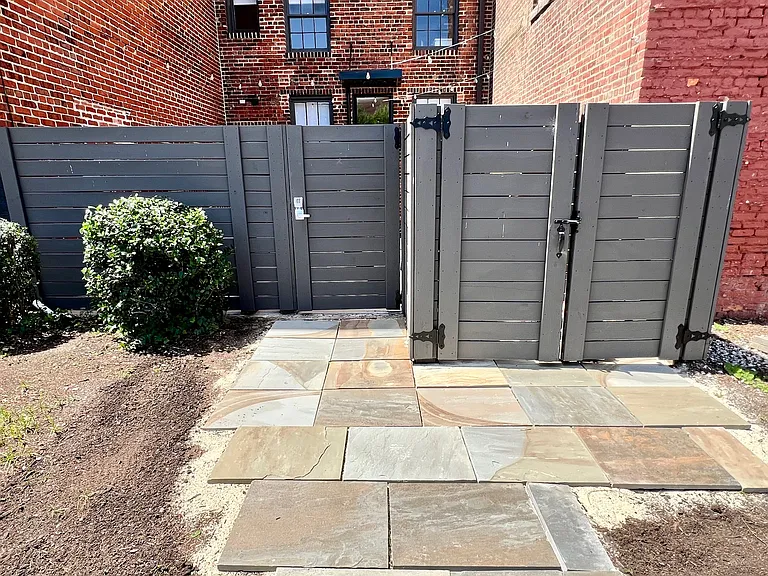 Exterior view of rear fence with Bluestone pavers and garbage enclosure.