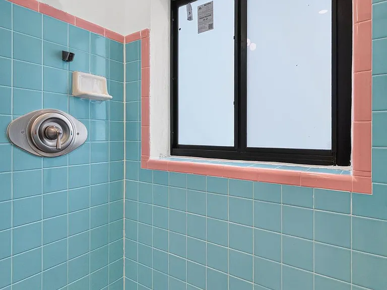 Walk-in shower with classic tile surround and a privacy window for natural light and ventilation.