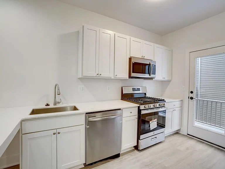 door to deck, 5 burner gas range, full size microwave, top mount controls on stainless tub dishwasher, side by side stainless frig w/ water & ice dispenser on outside of the door, quartz counters, pantry & more