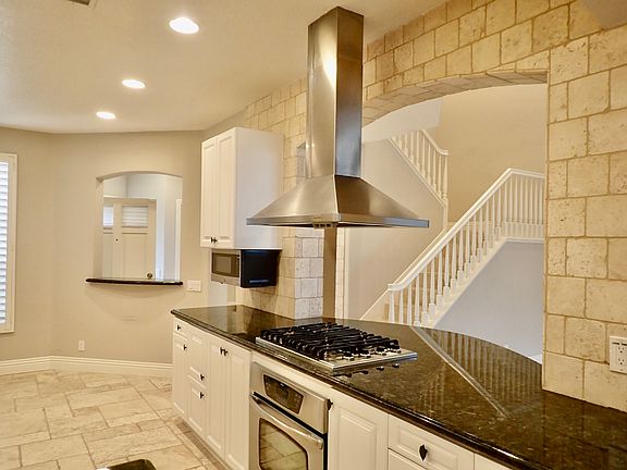 Custom stone, white cabinets, stainless appliances, and custom tile details