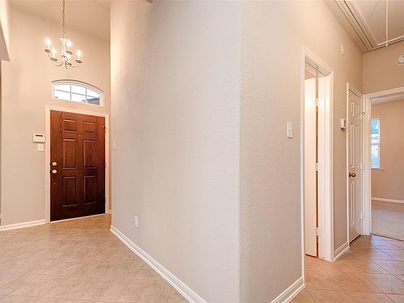 The entryway features a stylish chandelier and opens up to the hallway leading to the two secondary bedrooms and bathroom.