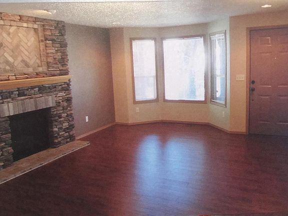 Open living room with bay window overlooking pond, and a gas
