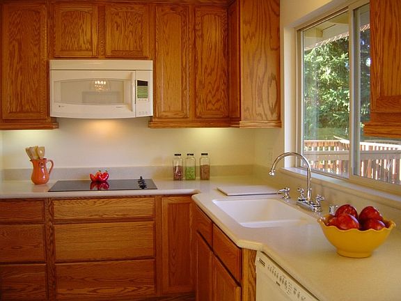 Updated kitchen with tons of storage! Tall cabinets, full extension deep drawers & solid surface countertops.