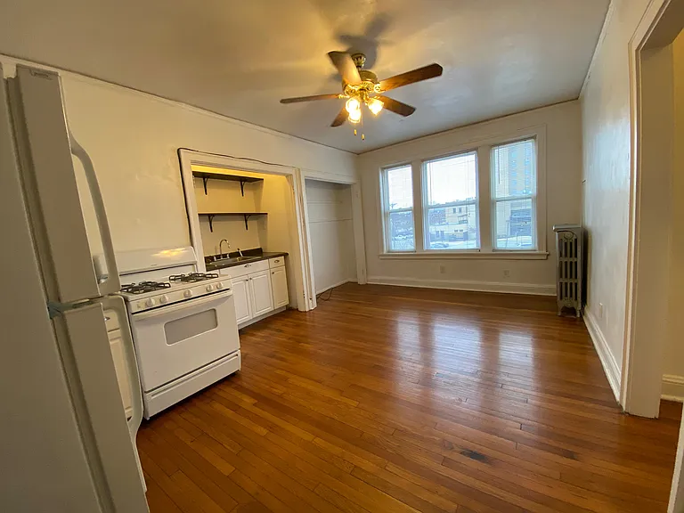 The kitchen and living room share one bright, versatile space, featuring beautiful hardwood floors, large windows, and plenty of room to arrange your living and dining areas to fit your lifestyle.