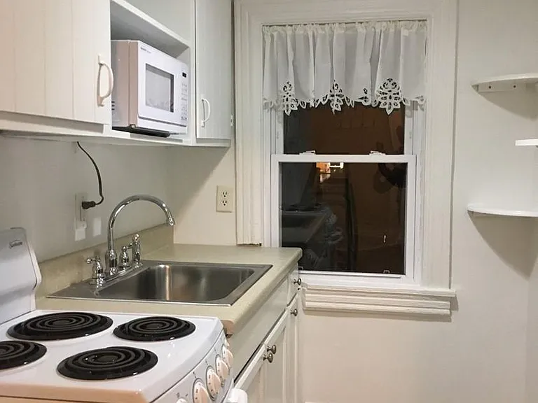 Kitchenette with apartment sized stove, microwave, sink.