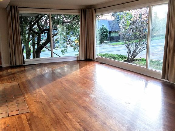 Enjoy the bright, sunny living room with floor-to-ceiling windows and hardwood floors