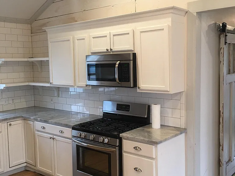 Stove, microwave, cabinets and marble countertops