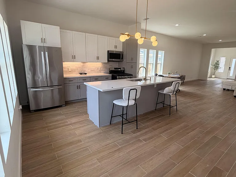 Open-concept kitchen with a large island, breakfast seating, and stainless appliances, flowing into the main living area.