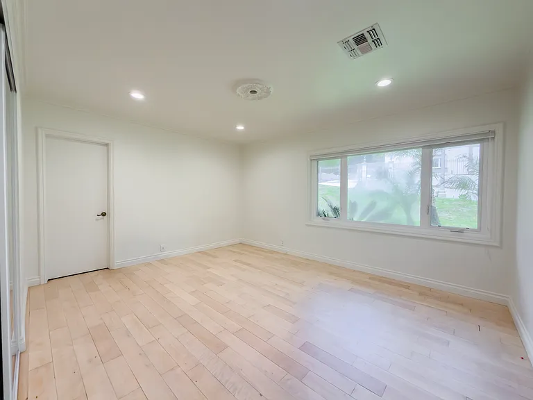 Corner windows flood this unfurnished bedroom with natural light, a bright retreat in this Beverly Hills luxury rental at 1094 Garden Lane, 90210.