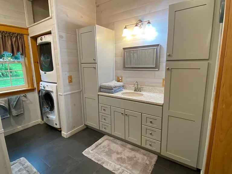 Wider view of bathroom with washer / dryer combination.