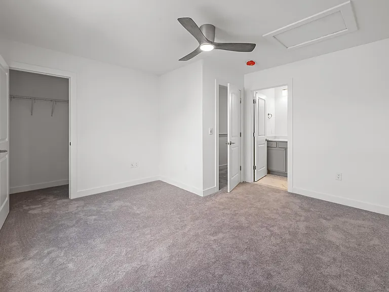 Primary BR with ceiling fan installed and walk in closet
