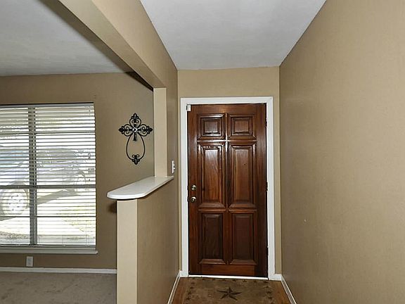 The foyer with a solid wood door and living room to the left