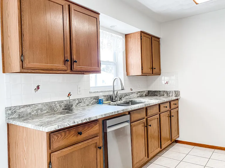 Bright kitchen has window above sink to look out into backyard. Brand new stainless dishwasher beside sink.