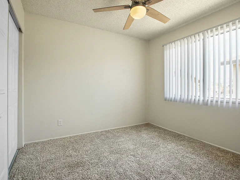 Bedroom with sliding closet door at the left, ceiling fan, carpeted flooring