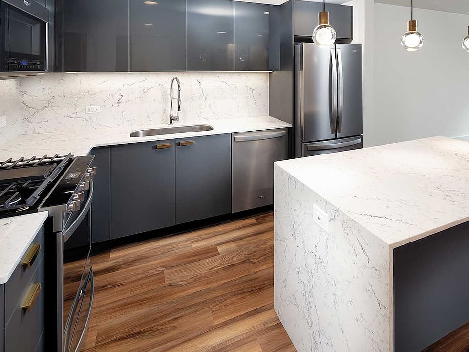 Signature Collection kitchen with pendant lighting, quartz stone countertop with waterfall edge, cabinetry with matte and high gloss finish, and SMART stainless steel appliances