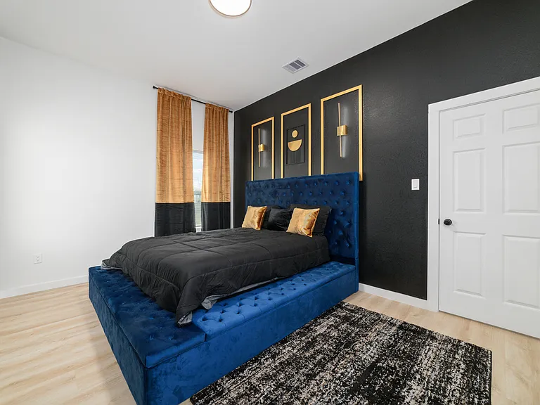 Master bedroom from closet view, Queen size bed, 55 inch smart TV, Lamp lights above bed on wall.