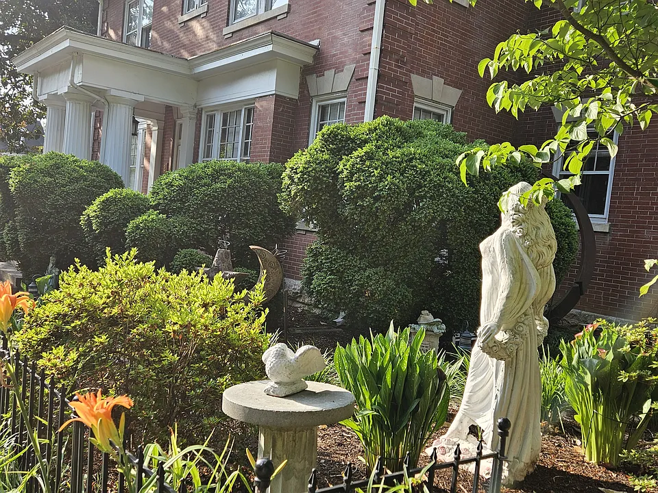Side of the apartment. Beautiful landscaping throughout the property. Can see columns to the apartment entrance.