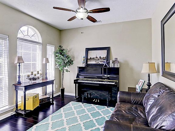 The formal living room has a triple window with half moon window detail, hardwood floors,and ceiling fan with light.